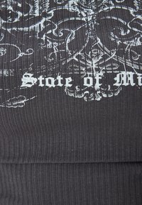 Dunkelgrauer, gerippter Stoff mit einer strukturierten Oberfläche, die weiße gedruckte Designs und die Phrase "State of Mind" in einer dekorativen Schriftart zeigt.