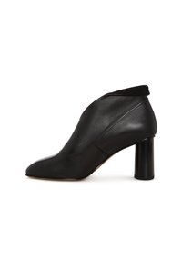 Stivale alla caviglia in pelle nera con tacco e punta affilata, caratterizzato da un design elegante e moderno su sfondo bianco.