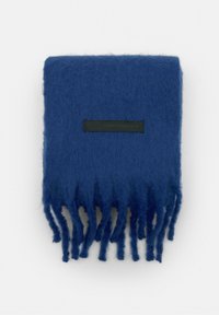 Blå uldscarf med frynser i enderne, med et sort mærke mærket "KLASSISK. MODERNE. DINER." Blød tekstur, rektangulær form.