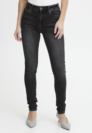 Zwarte skinny jeans van denim, met een hoge taille, vijf zakken en subtiele stikdetails, gecombineerd met grijze hoge hakken.