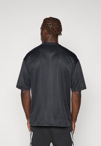 Korte mouwen zwart gestructureerd sportshirt met een ronde hals en subtiele patronen, gemaakt van lichtgewicht, ademend materiaal.