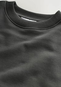 Nahaufnahme eines dunkelgrauen Sweatshirts mit Rundhalsausschnitt, das den gerippten Kragen und die glatte Baumwollstoffstruktur zeigt.