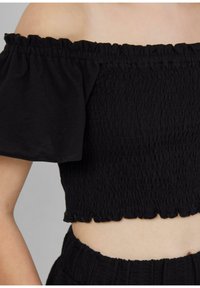 Schwarzes, schulterfreies Crop-Top mit gerüschten Ärmeln und einem gewellten Saum. Hergestellt aus leichtem Stoff.