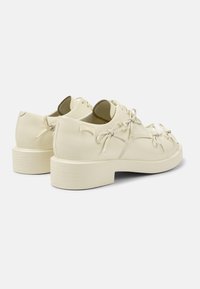 Scarpe color crema con lacci, caratterizzate da una texture liscia, con punta arrotondata e tacco a blocco. Accentuate da lacci in raso e dettagli con logo.