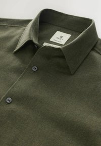 Cămașă verde din bumbac, cu o croială obișnuită, având guler, închidere cu nasturi, două butoane gri și un etichetă a mărcii la guler.