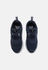 Baskets de sport navy avec tige en mesh, semelle blanche contrastante et détails texturés. Comprend des lacets et des tirants au niveau du talon.