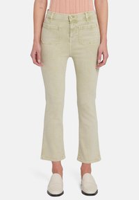 Lichtgroene denim flared jeans met een hoge taille, voor- en achterzakken en een zachte textuur. Gepaard met lichtgekleurde loafers.