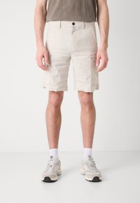 Beige cargo shorts med flere sidelommer, rett snitt, laget av lett materiale, med knappeåpning og en lett teksturert overflate.