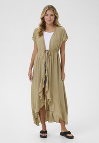 Beige, lightweight, long kimono-style dress with ruffled edges, drawstring waist, and short sleeves. Worn over a white top and shorts.