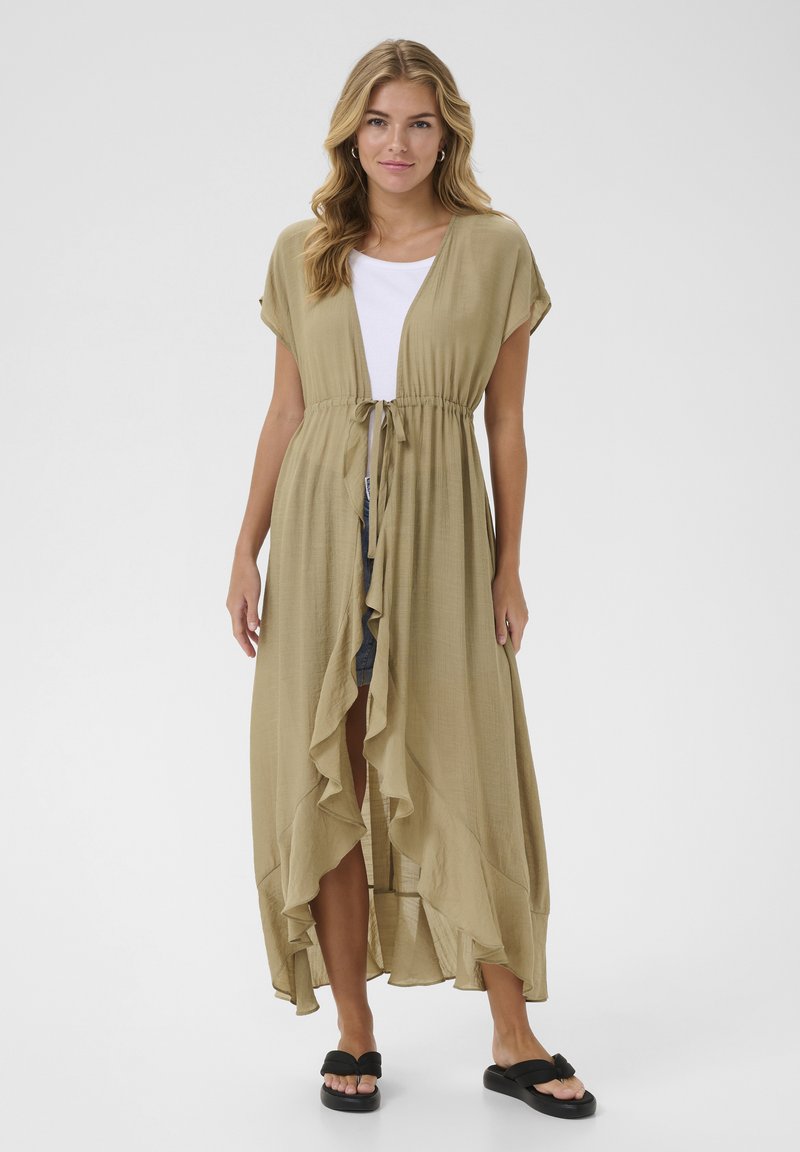 Beige, lightweight, long kimono-style dress with ruffled edges, drawstring waist, and short sleeves. Worn over a white top and shorts.