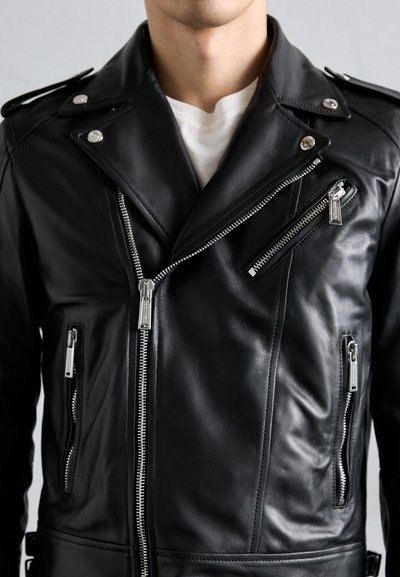 Giacca da motociclista in pelle nera con hardware argentato, chiusure a zip asimmetriche e molteplici tasche con zip. Texture liscia con collo a rever.
