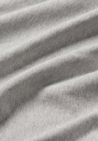 Sivi pamučni materijal s glatkom teksturom, koji sadrži suptilne horizontalne nabore i blage valove, stvarajući mekan i drapiran izgled.