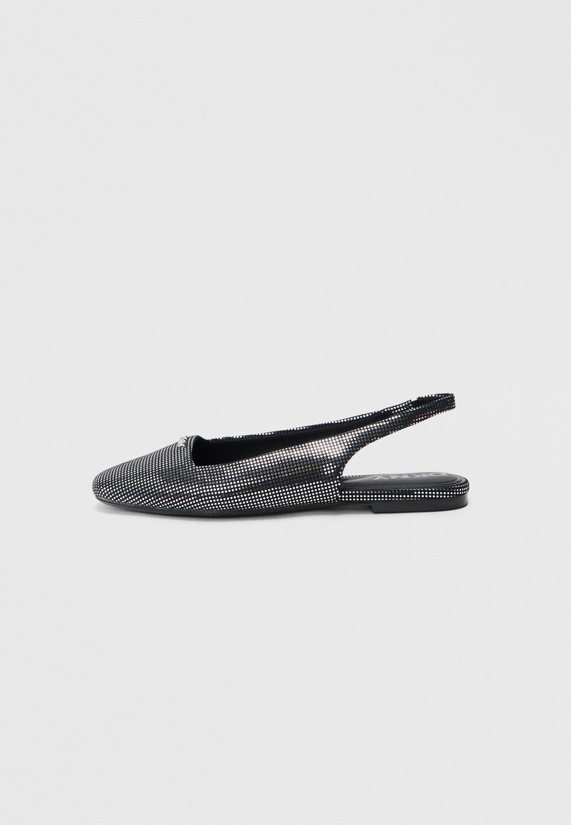 Chaussure plate noire à bride arrière avec bout pointu et clous argentés couvrant toute la surface, présentée sur un fond clair uni.