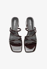 Mules en cuir verni marron foncé avec un bout carré, présentant plusieurs fines lanières entrelacées et un petit talon carré. Marquage sur la semelle intérieure.