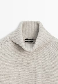 Pull à col roulé gris clair en maille côtelée, confectionné en laine 100 % avec un motif de point texturé.