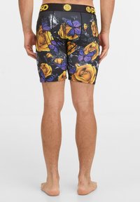 Pantaloni boxer con una base nera decorata con rose gialle e farfalle viola. Realizzati in un materiale elastico e morbido, con una vita nera.