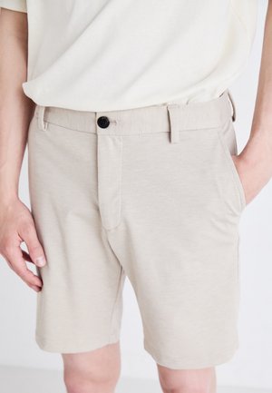 Hellbeige Shorts aus weichem Stoff, mit einer Vorderentasche und einem schwarzen Knopfverschluss am Bund. Gerader Schnitt.