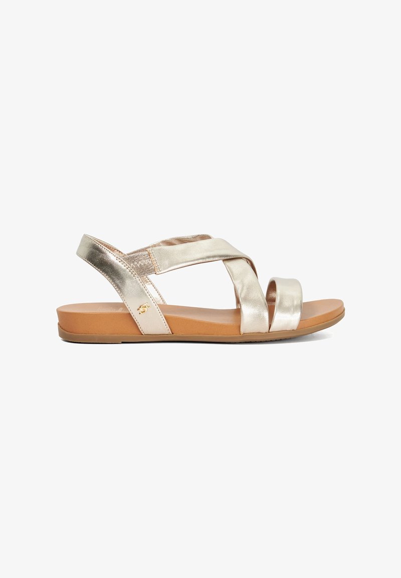 Metalen gouden sandalen met kruislings straps, een platte zool en een zachte tan voetbed. Bevat elastische accenten voor comfort en flexibiliteit.