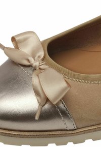 Ballerina con punta metallica argentata, tomaia in suede beige e decorazione in nastro di satin. Presenta una fodera interna imbottita e una suola in gomma.
