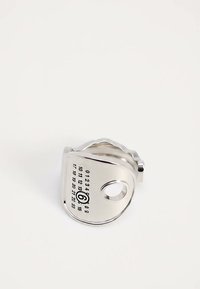 Anneau en métal ton argent avec des chiffres gravés de 0 à 23 et une découpe circulaire près d'un bord sur fond blanc.