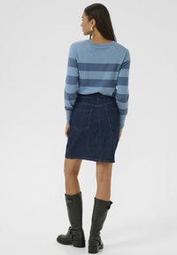 Blauw en lichtblauw gestreepte trui, donkere spijkerrok en zwarte kniehoog laarzen, met gladde texturen en een fitted ontwerp.