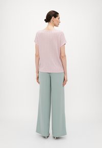 Top de rayas rosas con mangas cortas combinado con pantalones de pierna ancha en un suave tono verde menta. Texturas suaves y un ajuste relajado en toda la prenda.