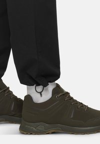 Olijfgroene wandelschoenen met een gestructureerde bovenkant, voorvetering en een robuuste zool. Draag met zwarte, taps toelopende broeken en witte, geribde sokken.