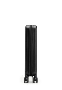 Valigia rigida nera con una finitura liscia e testurizzata, due ruote e chiusura a zip. Forma rettangolare slim, senza maniglie visibili.