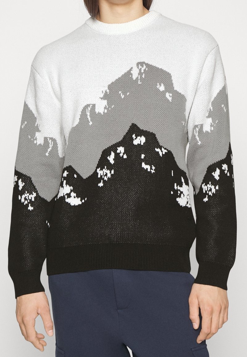 Maglione a maglia con motivo montano in nero, grigio e bianco. Collo a giro, maniche lunghe e polsini e orlo a coste.