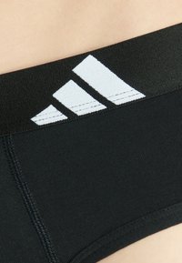 Svart atletisk kalsong med en mjuk midjeband som har en vit tre-stripes logotyp. Slät textur och sydda sömmar för hållbarhet.