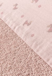 Soft pink fabric featuring a smooth top layer with a floral pattern and a textured, fluffy bottom layer in a matching hue.