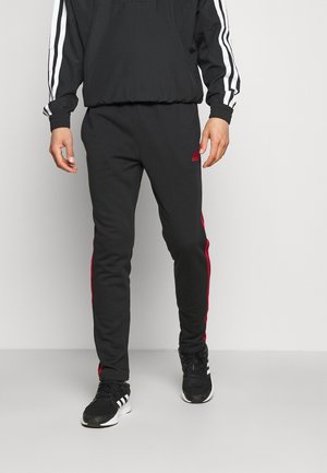 Pantaloni da jogging atletici neri con strisce laterali rosse, realizzati in tessuto morbido. Presentano una cintura elastica e una silhouette aderente.