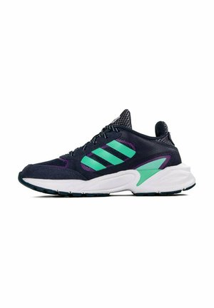 Scarpa sportiva blu navy con tomaia in mesh e suede, caratterizzata da accenti verdi e viola, una suola bianca imbottita e una suola esterna nera con trazione.