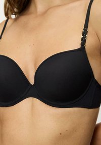 Czarny, wyściełany biustonosz z regulowanymi ramiączkami, z teksturowanym, tkanym detalem i złotymi, okrągłymi akcentami metalowymi. Gładkie matowe wykończenie.