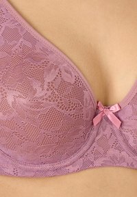 Reggiseno in pizzo di un morbido color lavanda con motivo floreale, caratterizzato da un dettaglio in raso a forma di fiocco al centro e bordi lisci.