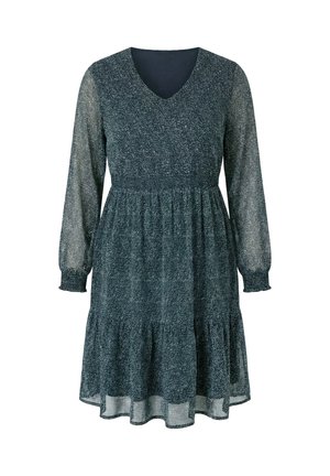 Tummanvihreä pitkähihaisen V-pääntien mekko, jossa on vyötärön kohdatut korsetti ja hieman levenevä, kerroksittain laskeutuva hame, jossa on hienovarainen valkoinen pilkullinen kuvio.