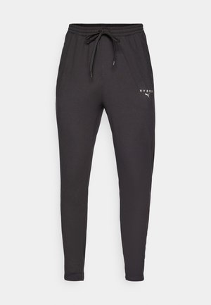 Juodi džinsai, pagaminti iš minkštos medžiagos, su elastine juosmeniu ir raišteliu, taip pat šoninėmis kišenėmis. Priekyje spausdintas baltas logotipas.