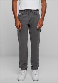 Šedé džíny cargo s bočními kapsami, standardní střih, zúžené nohavice a jemně vybledlá textura, spárované s bílými teniskami.