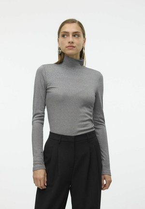 Haut à col roulé gris à manches longues, texture côtelée, design ajusté. Porté avec un pantalon noir taille haute.