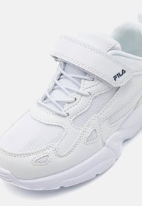 Baskets blanches de sport avec une tige en mesh et en cuir synthétique, des lacets et des fermetures à bande Velcro, et une semelle rembourrée avec des détails texturés.