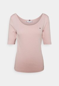 Růžové pruhované tričko s krátkými rukávy, širokým kulatým výstřihem a detailem loga na levé straně hrudníku. Měkký bavlněný materiál, přiléhavý střih.