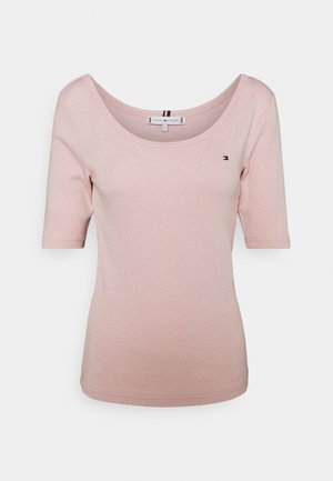 Vaaleanpunainen ribbattu t-paita lyhyillä hihoilla, leveällä pyöreällä pääntiellä ja logoyksityiskohdalla vasemmassa rinnassa. Pehmeää puuvillamateriaalia, istuva malli.