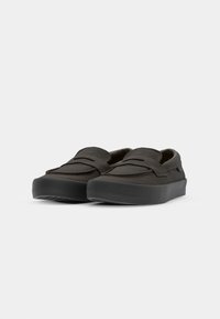 Mørkegrå slip-onsko med rund tå, som har et teksturert overdel og en tykk svart såle. Minimalistisk design uten synlige festemidler.