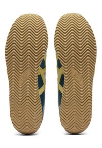 Sneaker outsole with a wavy texture. Features brown rubber with a light tan midsole, highlighted by a yellow design and logo detail.