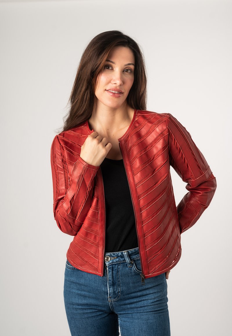 Rode leren jasje met verhoogde diagonale strepen, een ritssluiting aan de voorkant en een ronde halslijn, gecombineerd met een zwart topje en blauwe jeans.