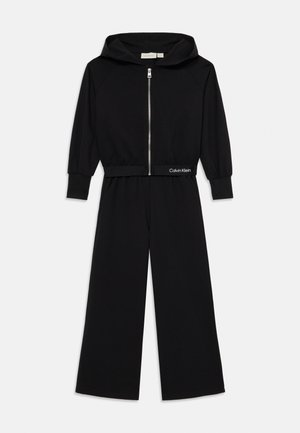 Svart hettegenser med lange ermer og glidelås foran. Har en tettsittende midje med Calvin Klein-logo, laget av mykt stoff.