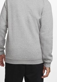 Sudadera gris con mangas largas, puños acanalados y dobladillo inferior. El material parece suave y texturizado, con un diseño liso.