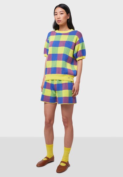 Conjunto de punto colorido con un patrón a cuadros en azul, amarillo y púrpura. Top de manga corta y pantalones cortos a juego, con acentos amarillos.