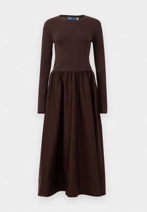 Pruun pika varrukaga kleit, millel on kitsas ülemine osa ja laienev, kogutud seelik. Valmistatud pehmest puuvillast, omades ümmargust kaelust ja pahkluuni ulatuvat pikkust.