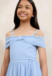 Robe bleue clair avec des manches dénudées et un détail de nœud à l'avant. Fabriquée en tissu léger, elle présente une taille cintrée et une jupe évasée.